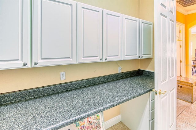 kitchen featuring crown molding, light tile floors, and white cabinets