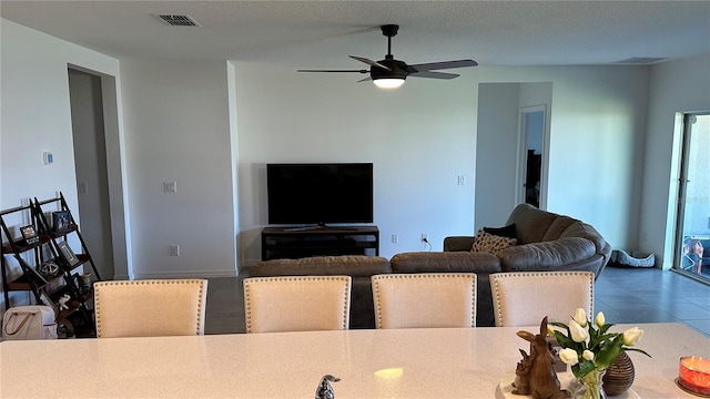 living room with dark tile floors and ceiling fan