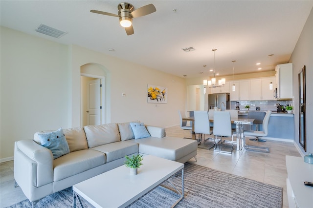 tiled living room featuring ceiling fan with notable chandelier