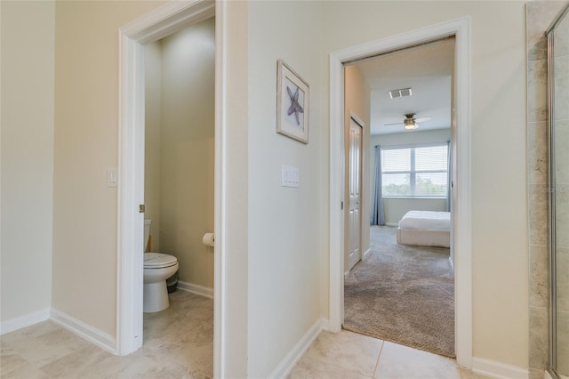 bathroom featuring toilet, tile flooring, and a shower with shower door