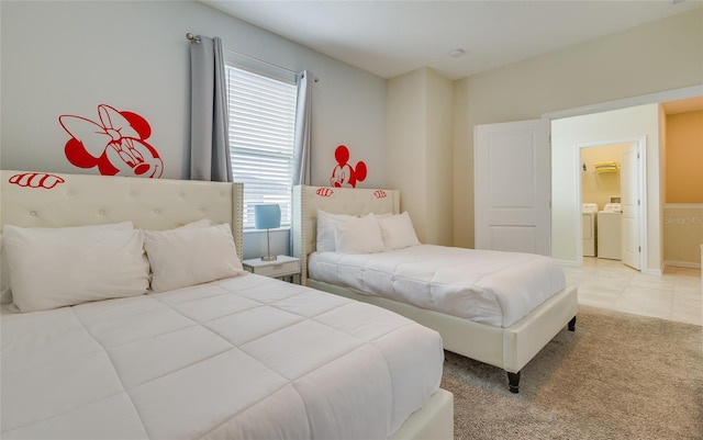 bedroom featuring light tile floors, ensuite bathroom, and washing machine and clothes dryer