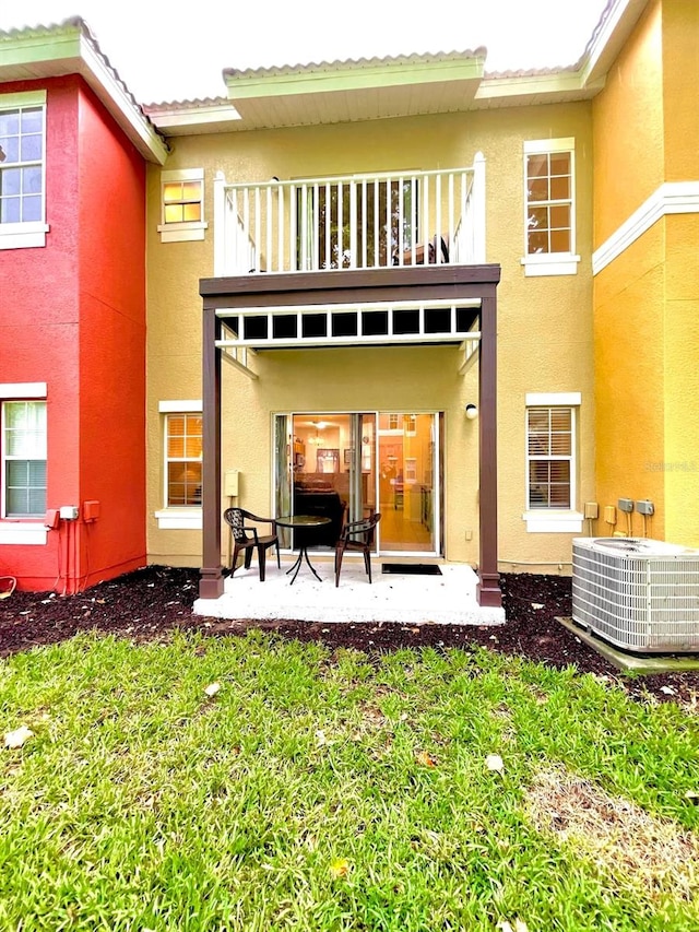 rear view of house with central air condition unit, a balcony, and a patio