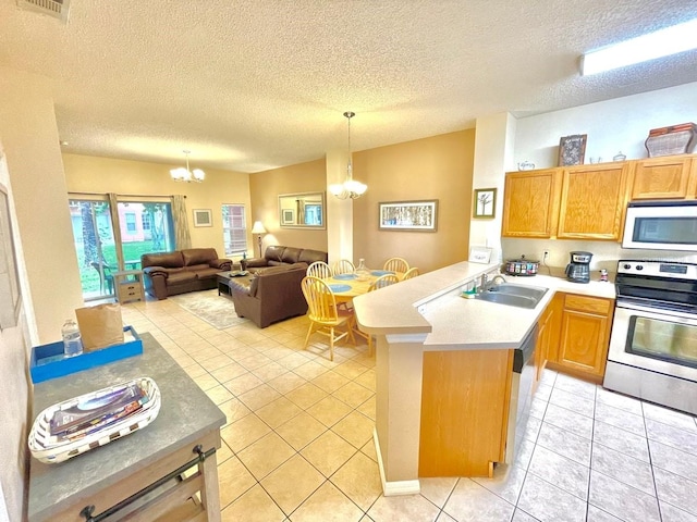 kitchen featuring kitchen peninsula, a textured ceiling, stainless steel appliances, sink, and an inviting chandelier