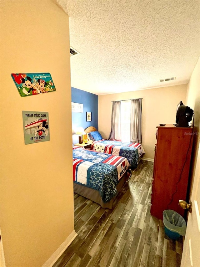 bedroom featuring a textured ceiling and dark wood-type flooring