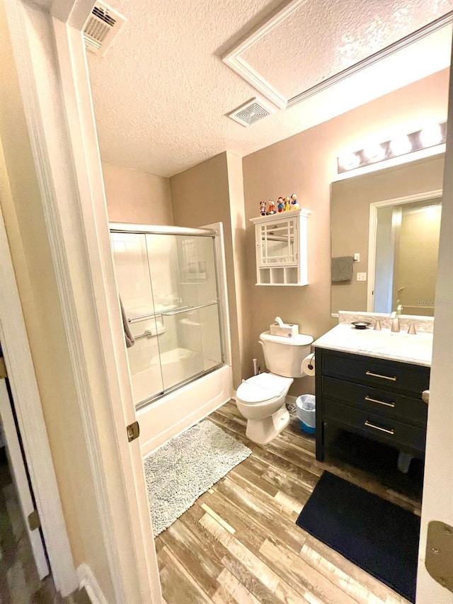 full bathroom with enclosed tub / shower combo, a textured ceiling, toilet, vanity, and hardwood / wood-style flooring