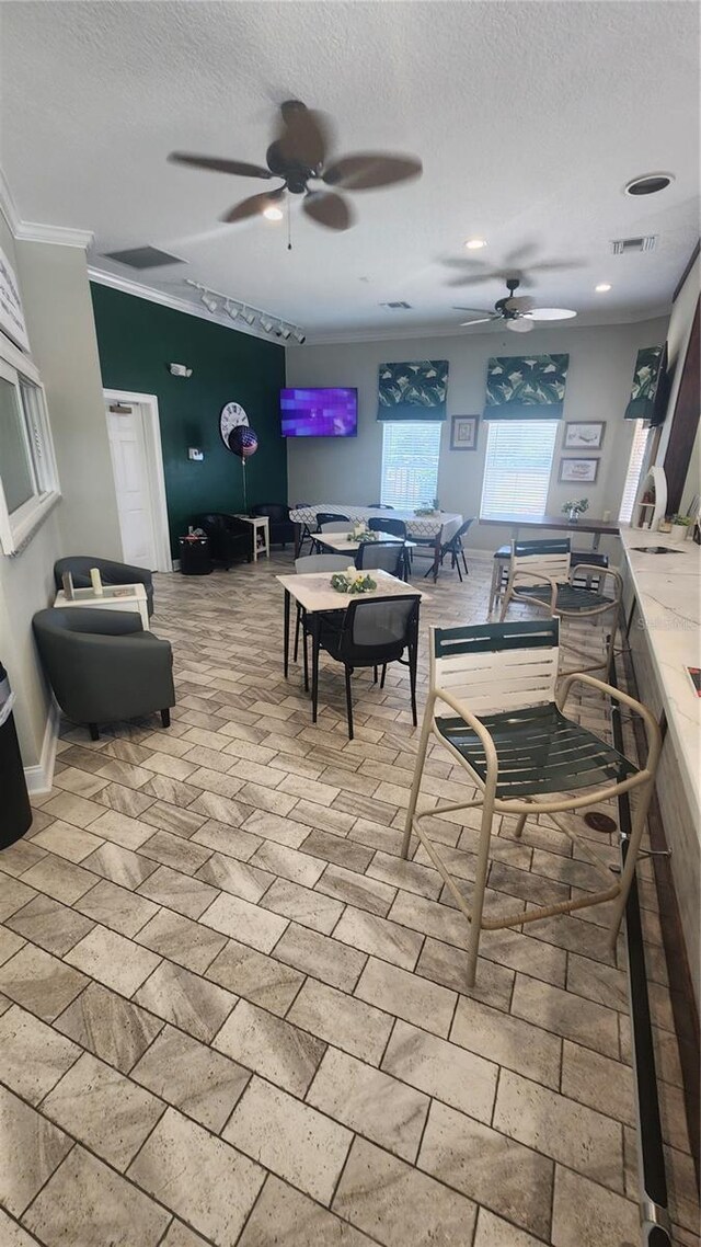 dining area featuring a textured ceiling, ceiling fan, and crown molding
