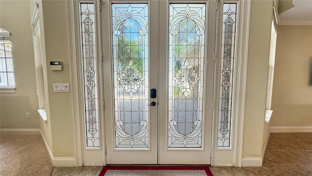 entryway with ornamental molding, light tile floors, and french doors