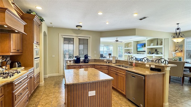 kitchen featuring stainless steel appliances, a center island, ceiling fan, premium range hood, and decorative light fixtures