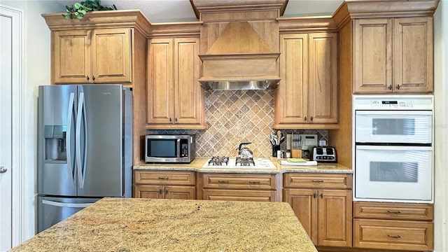 kitchen with appliances with stainless steel finishes, backsplash, light stone counters, and custom range hood