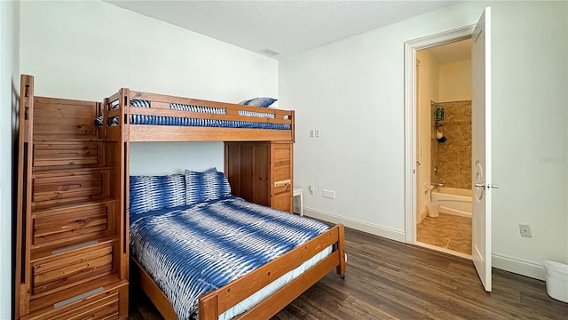 bedroom featuring ensuite bath, dark wood-type flooring, and a textured ceiling