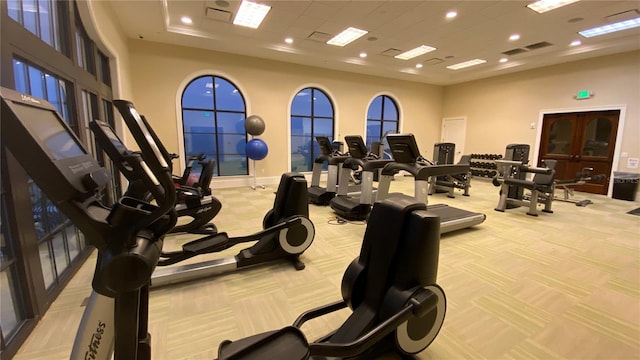 workout area with light colored carpet and a high ceiling