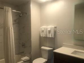 full bathroom with vanity, shower / bath combination with curtain, and toilet