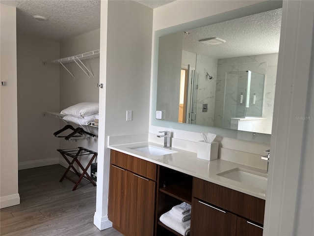 bathroom with hardwood / wood-style flooring, vanity, an enclosed shower, and a textured ceiling