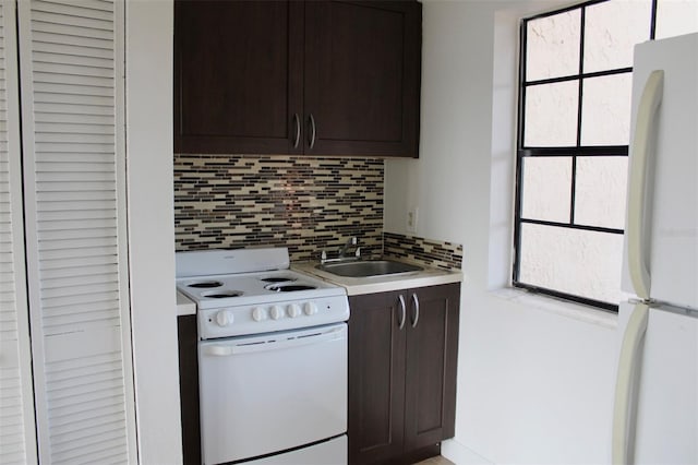 kitchen with dark brown cabinets, tasteful backsplash, white appliances, and sink