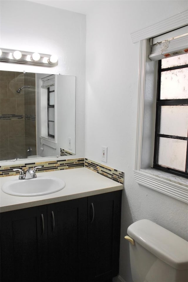 bathroom featuring toilet, vanity, and tiled shower