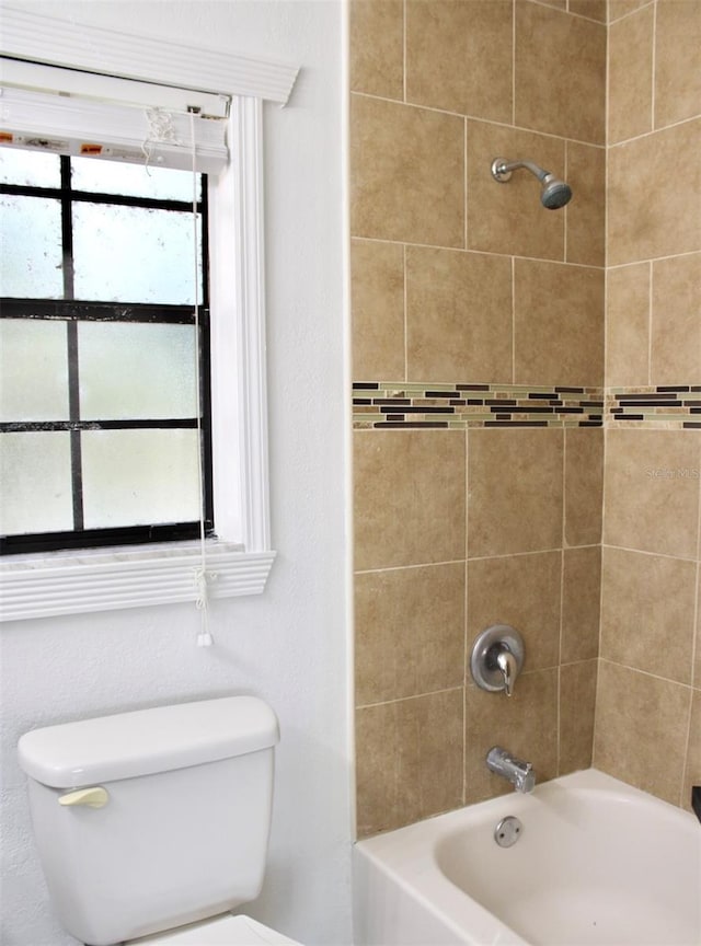 bathroom featuring toilet and tiled shower / bath combo