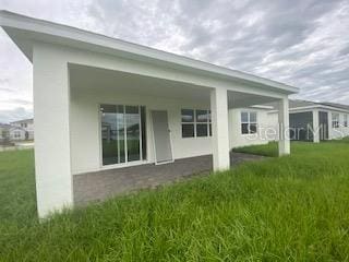 rear view of property featuring a yard and stucco siding