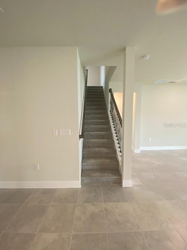 staircase featuring tile patterned floors and baseboards