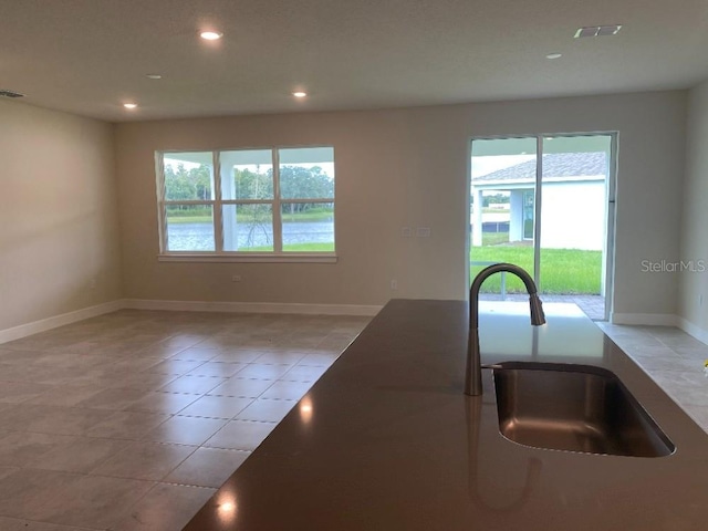 kitchen featuring baseboards, recessed lighting, visible vents, and a sink