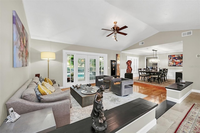 living room featuring french doors, lofted ceiling, ceiling fan with notable chandelier, and light wood-type flooring