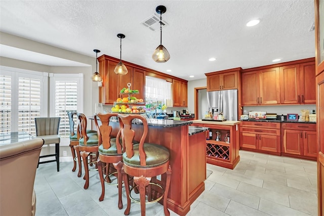 kitchen featuring light tile floors, stainless steel fridge with ice dispenser, hanging light fixtures, and a healthy amount of sunlight