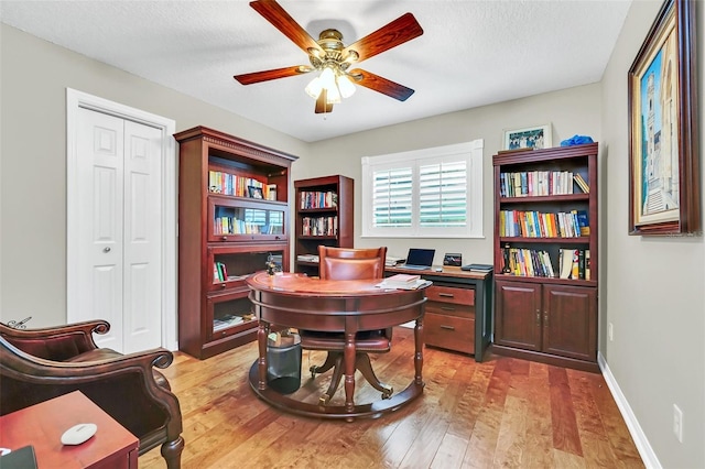 office space featuring ceiling fan, light hardwood / wood-style flooring, and a textured ceiling