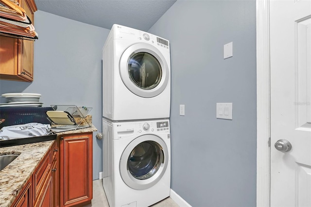 laundry room with cabinets, stacked washer and dryer, and light tile flooring