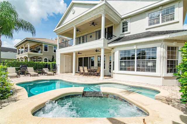 rear view of house featuring a balcony, a patio area, a pool with hot tub, and ceiling fan