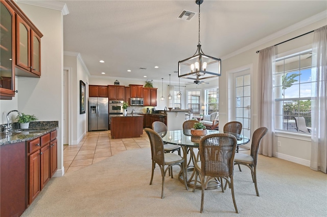 carpeted dining room with ceiling fan with notable chandelier, sink, and crown molding