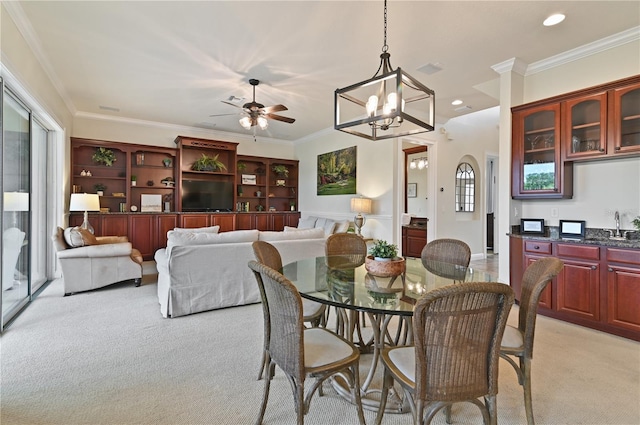 carpeted dining space featuring ceiling fan with notable chandelier, a wealth of natural light, and crown molding