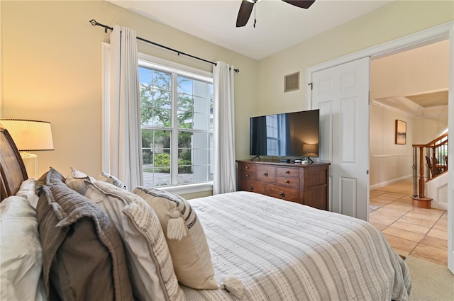 bedroom featuring ceiling fan, light tile patterned flooring, and multiple windows