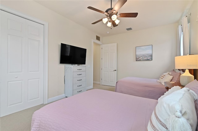 bedroom featuring light carpet, ceiling fan, and a closet