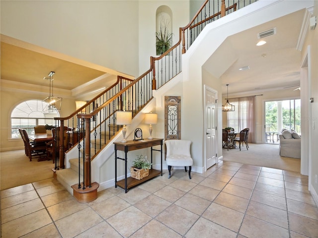 staircase with tile patterned floors, ornamental molding, and an inviting chandelier