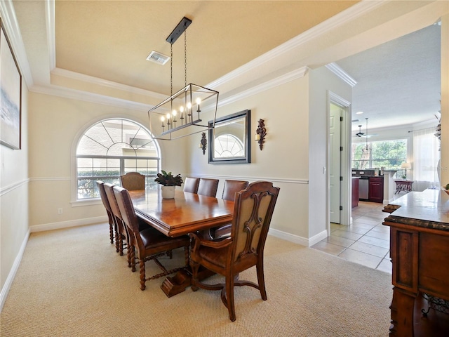 carpeted dining room with ceiling fan with notable chandelier, a raised ceiling, and ornamental molding