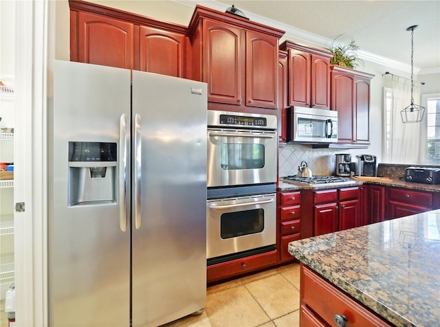 kitchen with hanging light fixtures, stainless steel appliances, ornamental molding, light tile patterned floors, and dark stone counters