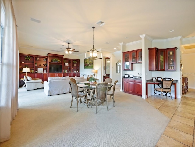 dining room featuring ceiling fan, sink, ornamental molding, and light carpet