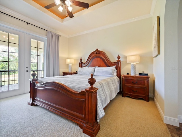 carpeted bedroom featuring ceiling fan, access to exterior, a raised ceiling, crown molding, and french doors