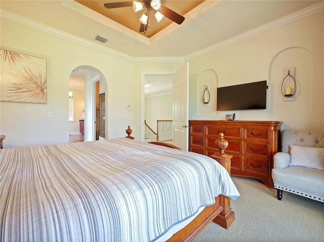 carpeted bedroom featuring a raised ceiling, ceiling fan, and crown molding