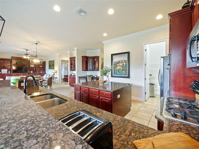 kitchen with appliances with stainless steel finishes, sink, hanging light fixtures, ornamental molding, and light tile patterned floors