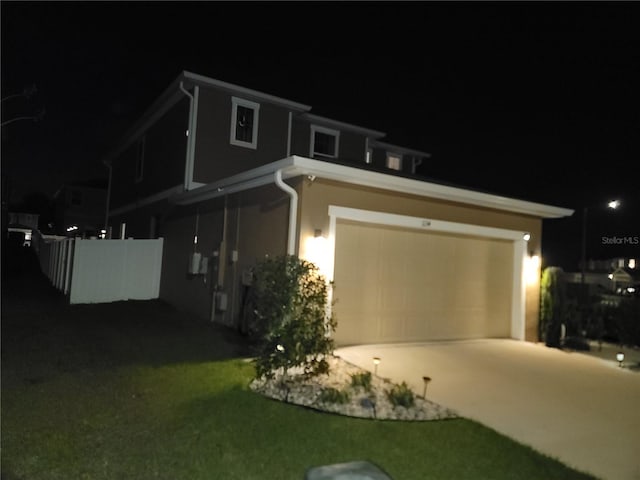 view of front of home with a lawn, concrete driveway, a garage, and fence