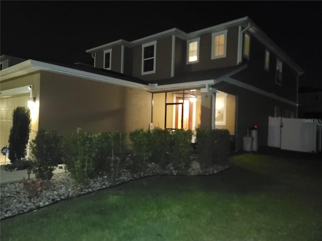 property exterior at night featuring a garage and stucco siding