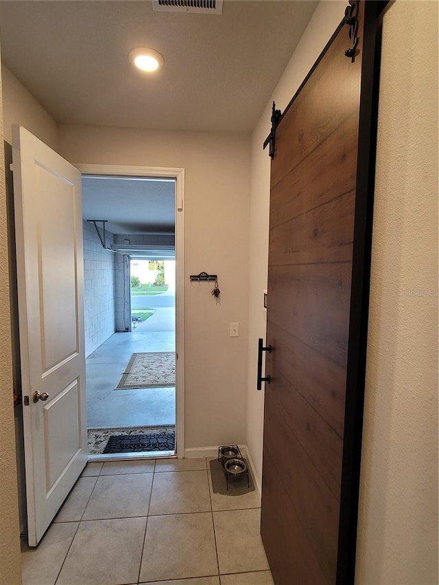 doorway featuring a barn door, baseboards, visible vents, and light tile patterned flooring