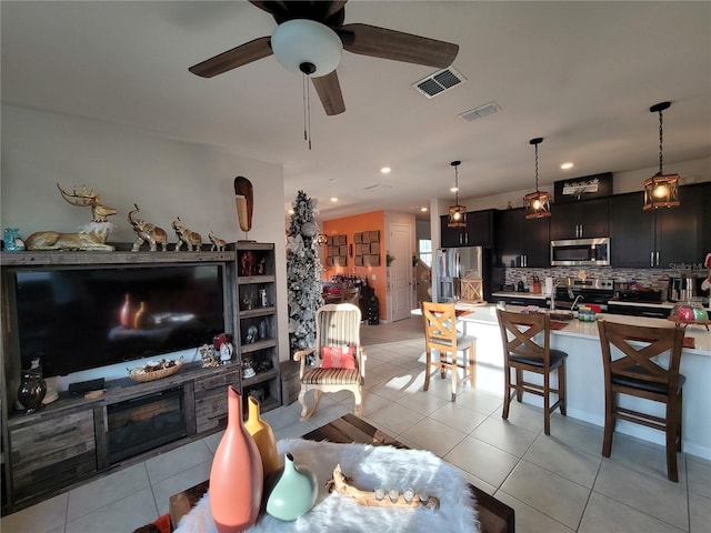 living area with light tile patterned floors, visible vents, recessed lighting, and a ceiling fan