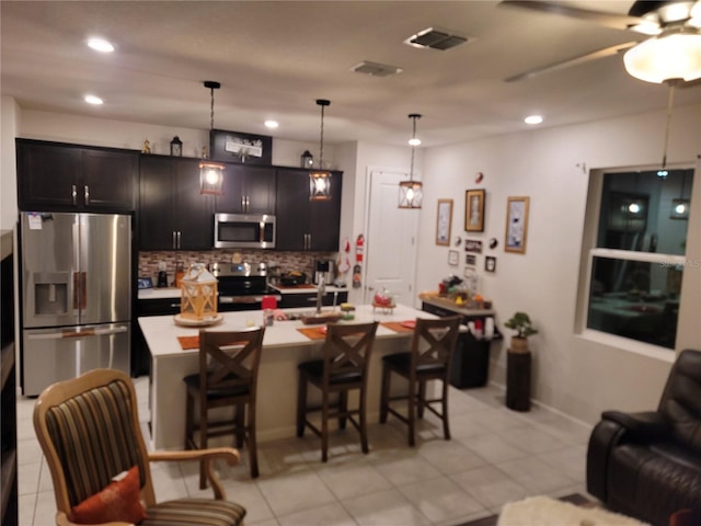 kitchen with a breakfast bar area, visible vents, light countertops, appliances with stainless steel finishes, and backsplash