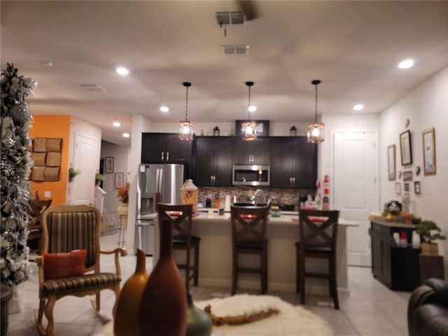 kitchen with a kitchen bar, pendant lighting, appliances with stainless steel finishes, light countertops, and decorative backsplash