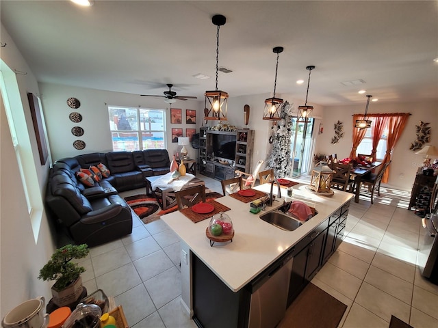 kitchen featuring stainless steel dishwasher, light countertops, light tile patterned floors, and a sink