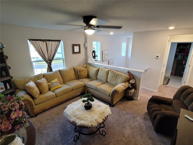 living area with a wealth of natural light, light carpet, a textured ceiling, and a ceiling fan