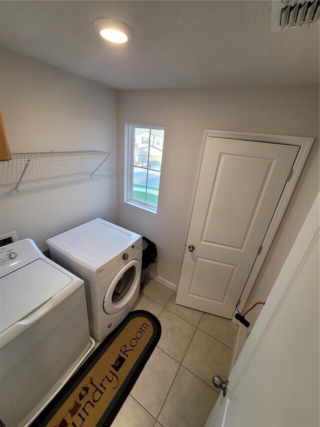 washroom featuring laundry area, light tile patterned floors, separate washer and dryer, and visible vents