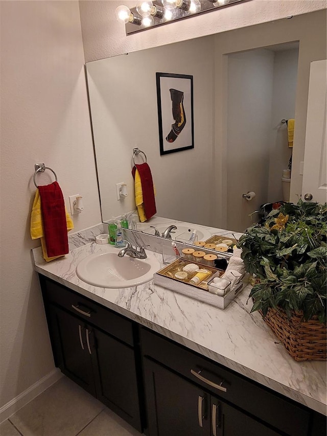 half bathroom featuring tile patterned flooring, toilet, vanity, and baseboards