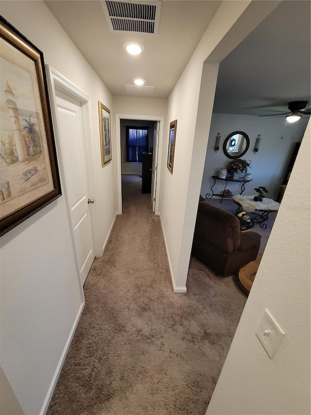 hall featuring visible vents, baseboards, and carpet flooring